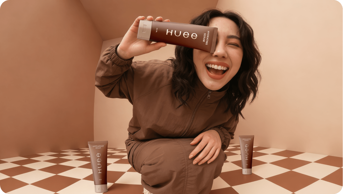 Smiling woman holding Huee skincare product on brown checkered floor